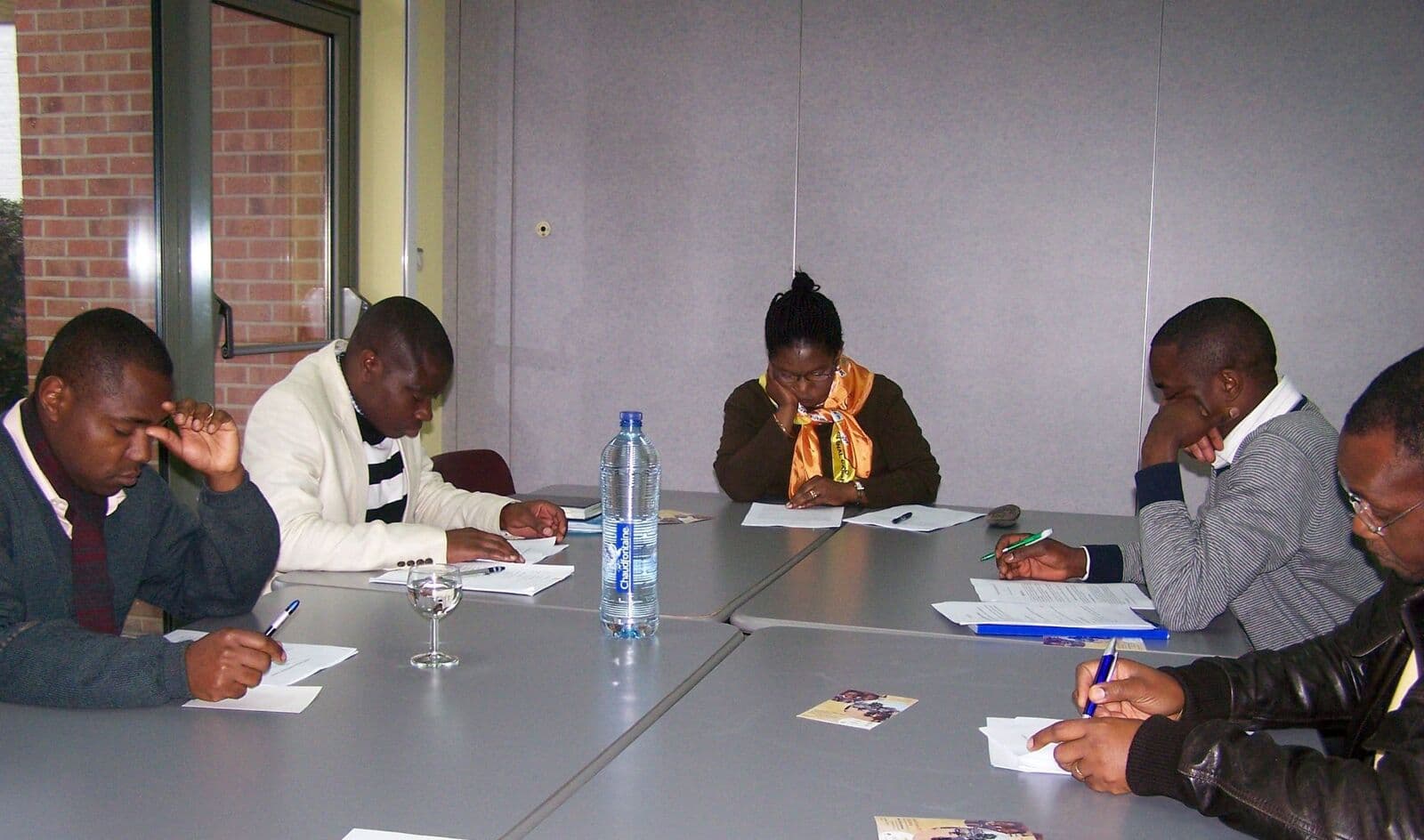 Cinq participants lisent et annotent des documents autour d’une table.